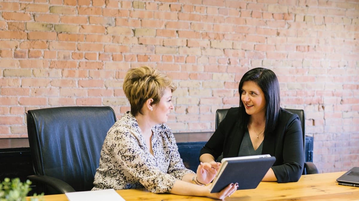 Two professionals reviewing a tablet together at a wooden table while planning how an Ontario therapy practice gets more private clients