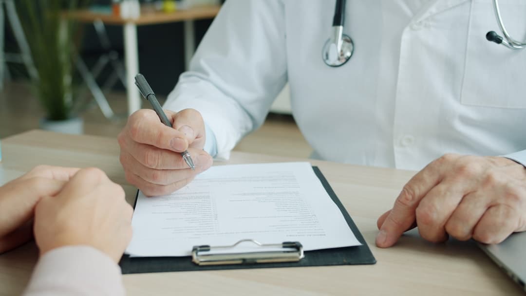 A doctor reviewing a one-page document, illustrating the importance of crafting effective leave-behinds for referrals.