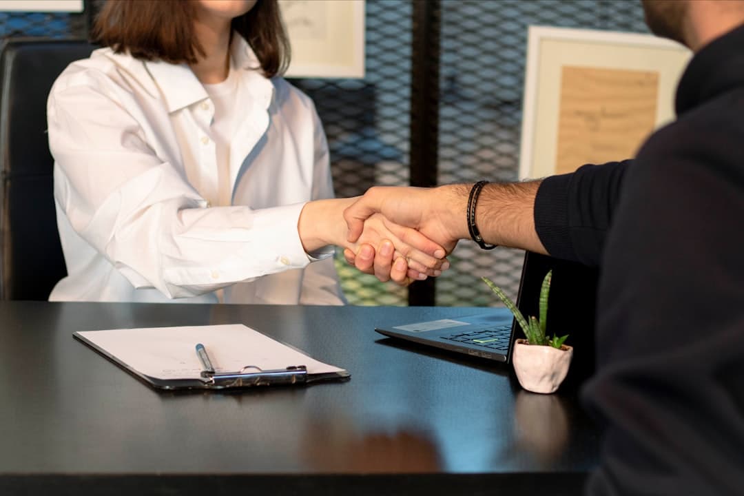 Two professionals shaking hands in an office, symbolizing the creation of a referral agreement between therapists and GPs.